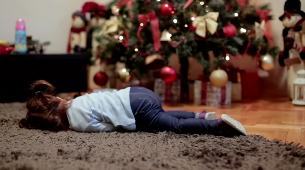 Little girl waiting for her Christmas present lying on the floor